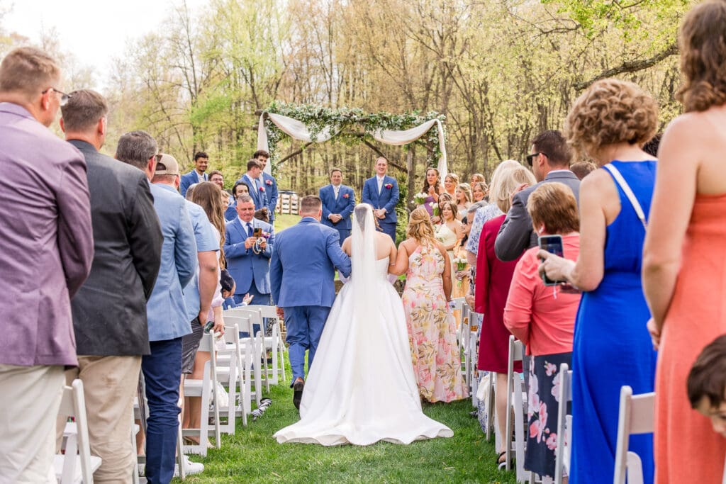 Bride walks down the aisle with her parents at Rivercrest Farms in Dover, Ohio.