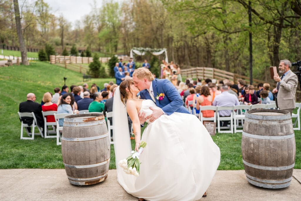 Couple dip kiss during their recessional at Rivercrest Farms in Dover, Ohio.