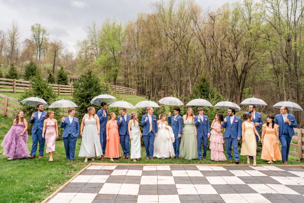 A large, colorful wedding party with umbrellas at Rivercrest Farms in Dover, Ohio.