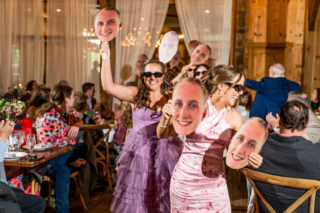 Bridesmaids hold up a cardboard cutout of the groom as they enter the reception.