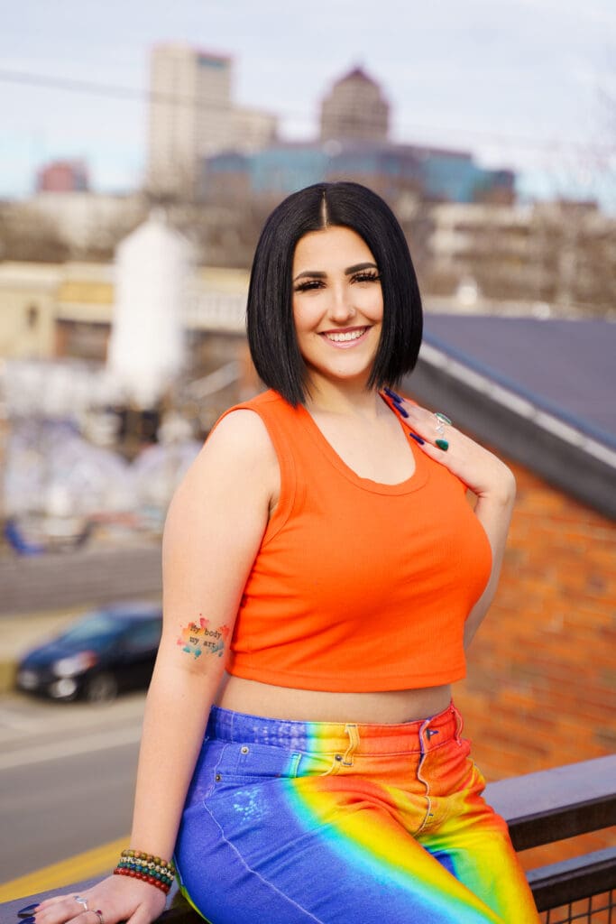 Senior in bright streetwear on a rooftop in Franklinton Columbus, Ohio.