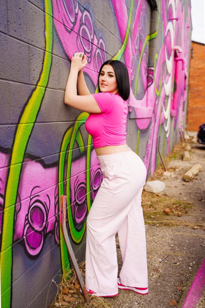 Senior in a bright outfit by graffiti in Franklinton Columbus, Ohio.