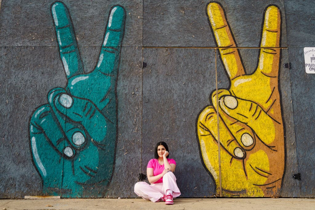 Senior in a bright pink outfit by graffiti in Franklinton Columbus, Ohio.