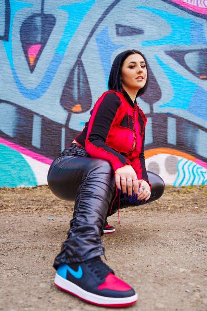 Senior in streetwear by graffiti in Franklinton Columbus, Ohio.