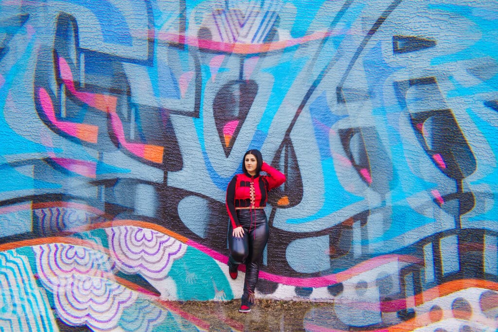 Senior in streetwear by graffiti in Franklinton Columbus, Ohio.