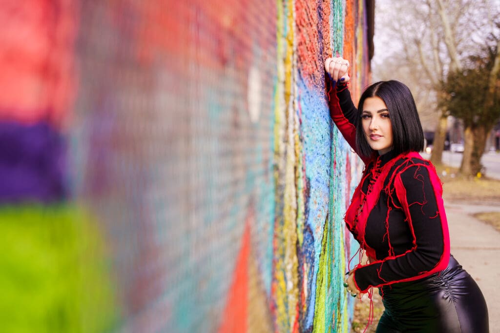 Senior in streetwear by graffiti in Franklinton Columbus, Ohio.