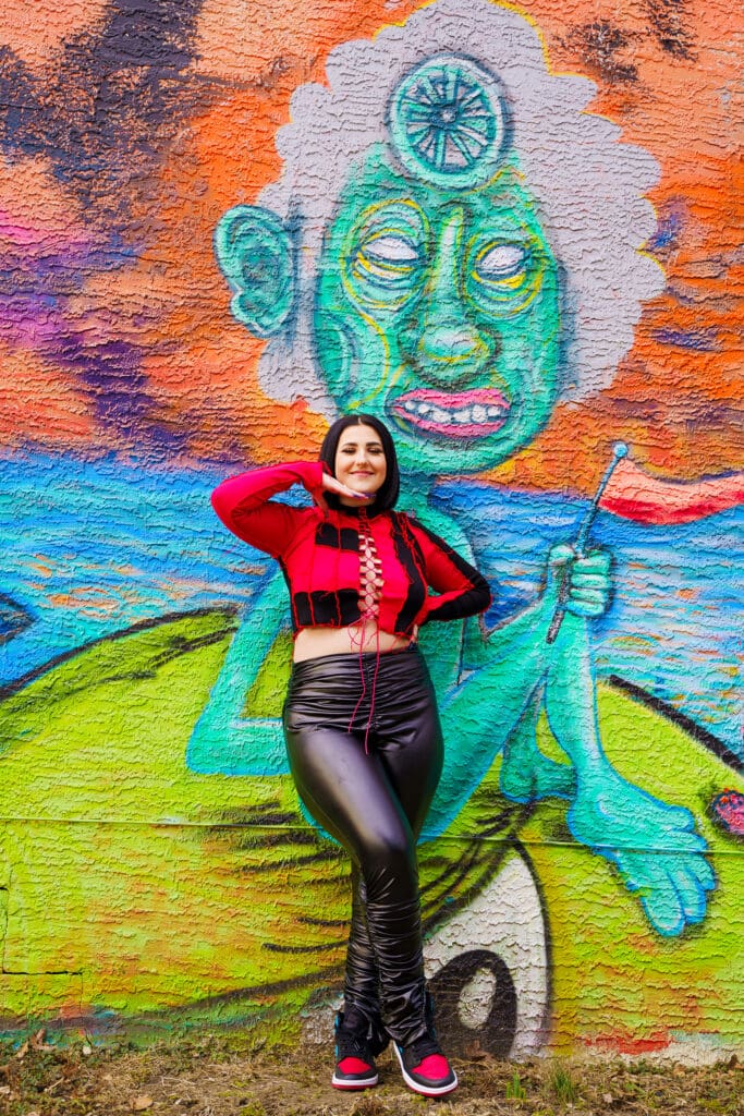 Senior in streetwear by graffiti in Franklinton Columbus, Ohio.