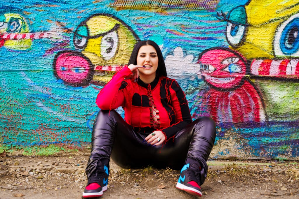 Senior in streetwear by graffiti in Franklinton Columbus, Ohio.