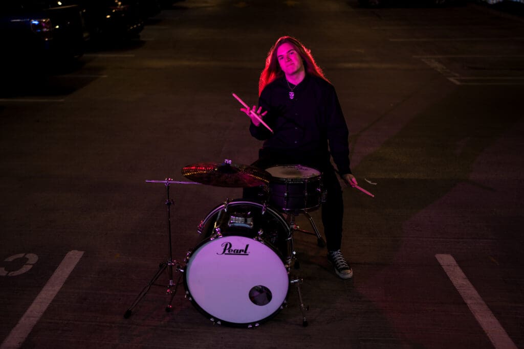 Senior with drum set in a parking garage in Columbus, Ohio.