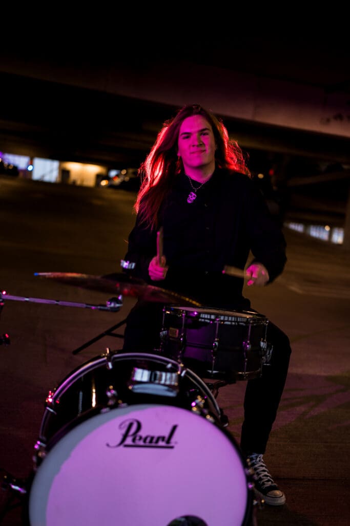 Senior with drum set in a parking garage in Columbus, Ohio.
