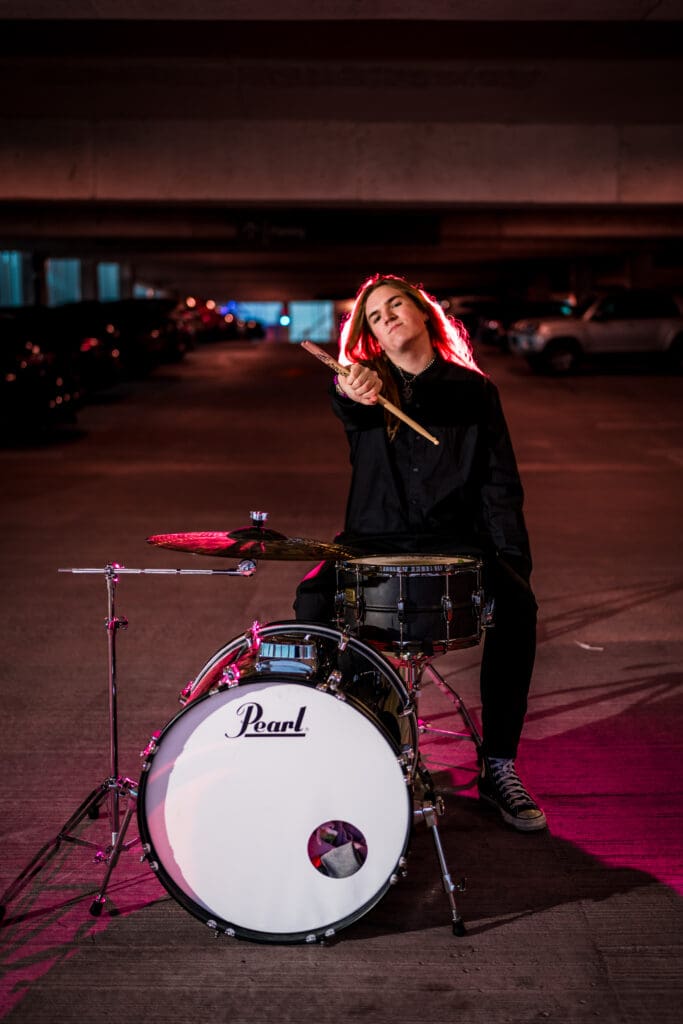 Senior with drum set in a parking garage in Columbus, Ohio.