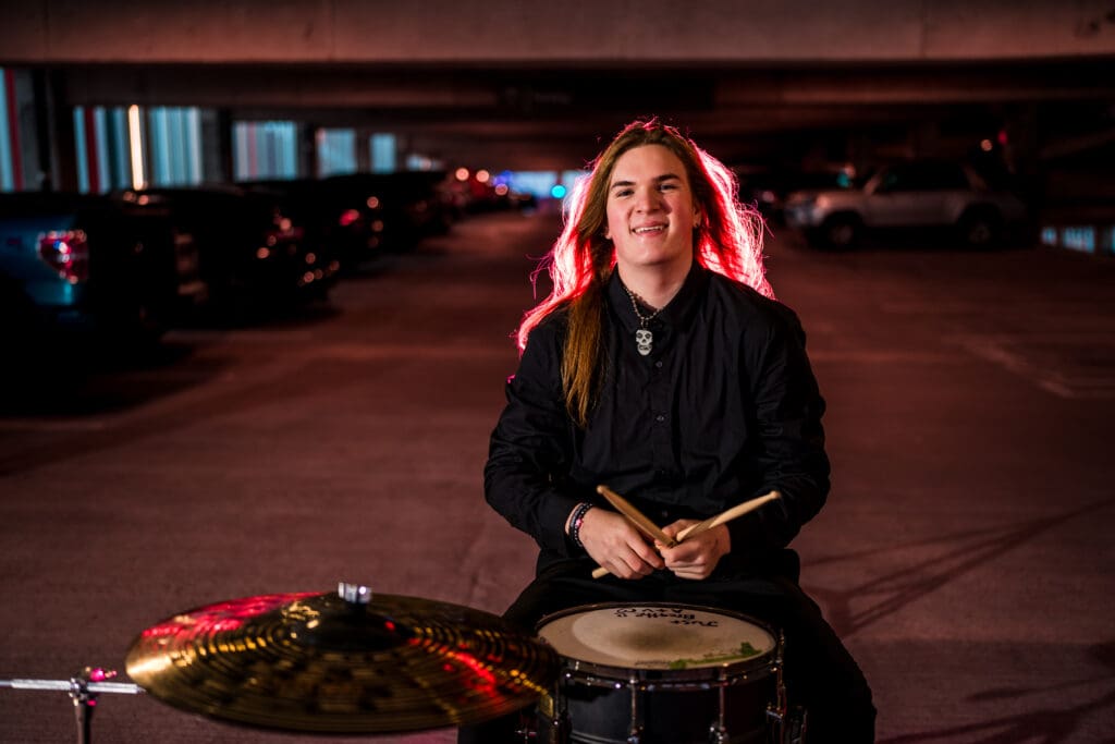 Senior with drum set in a parking garage in Columbus, Ohio.