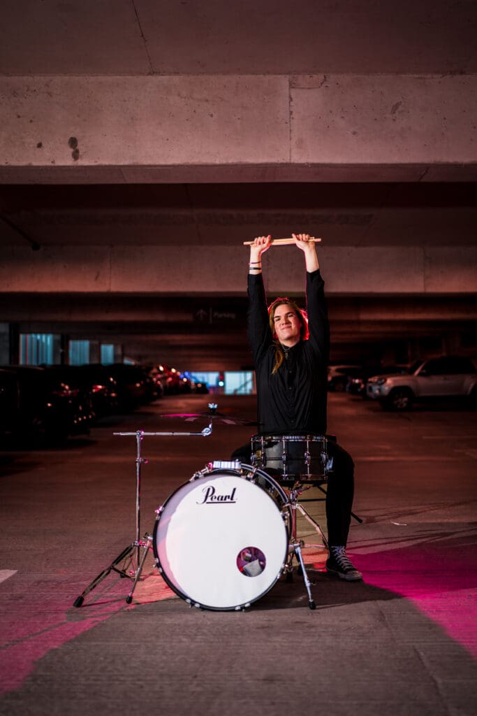 Senior with drum set in a parking garage in Columbus, Ohio.