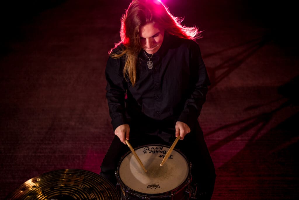 Senior with drum set in a parking garage in Columbus, Ohio.