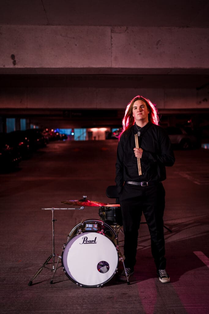 Senior with drum set in a parking garage in Columbus, Ohio.