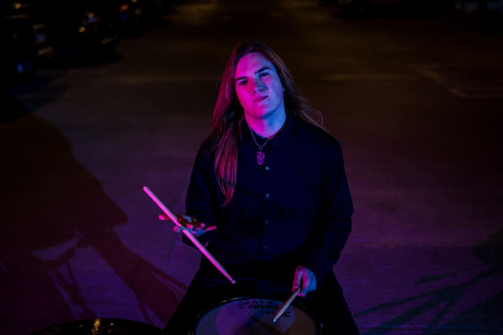 Senior with drum set in a parking garage in Columbus, Ohio.