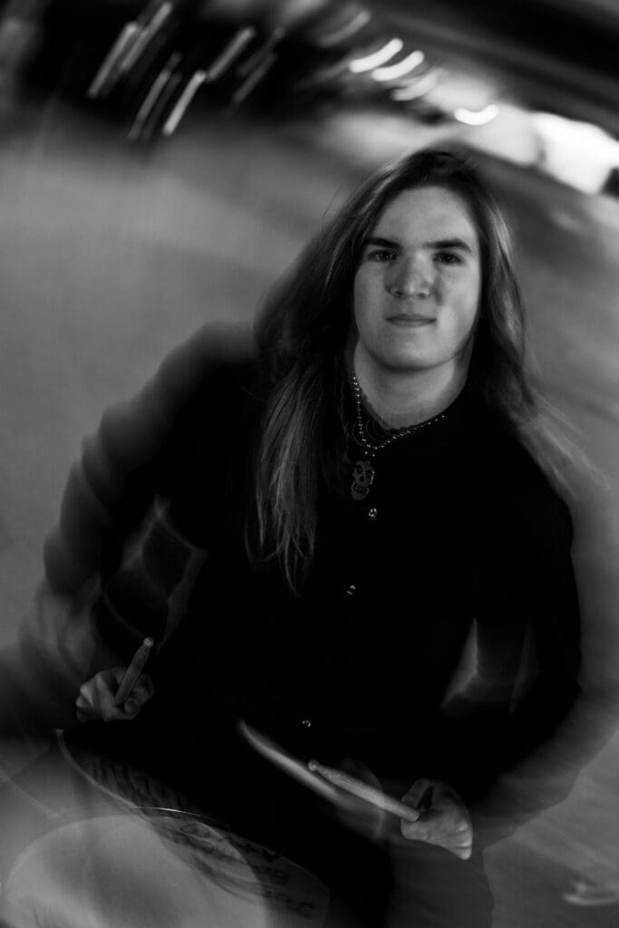 Senior with drum set in a parking garage in Columbus, Ohio.