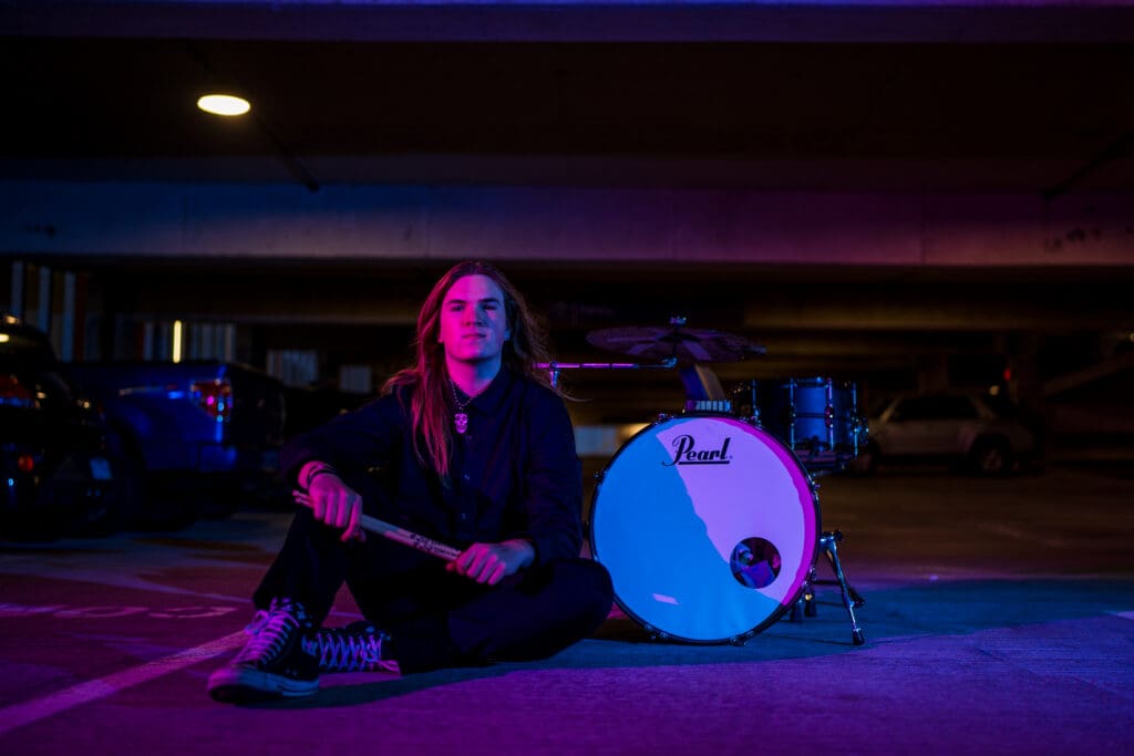 Senior with drum set in a parking garage in Columbus, Ohio.