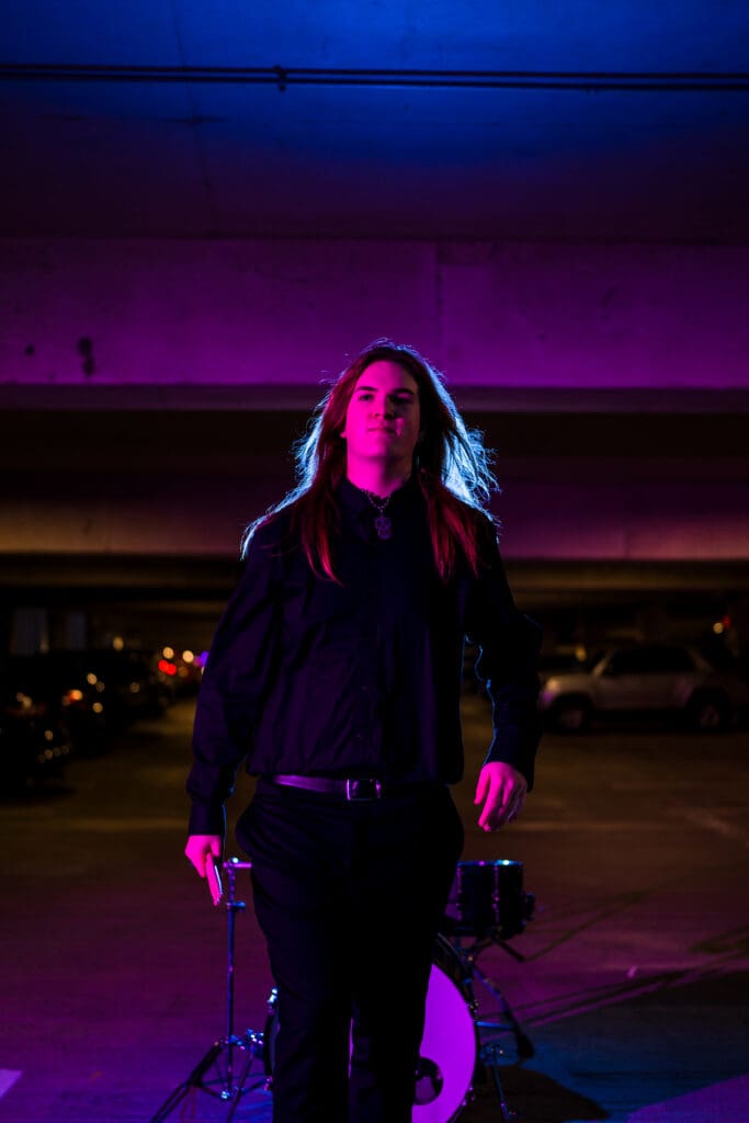 Senior with drum set in a parking garage in Columbus, Ohio.