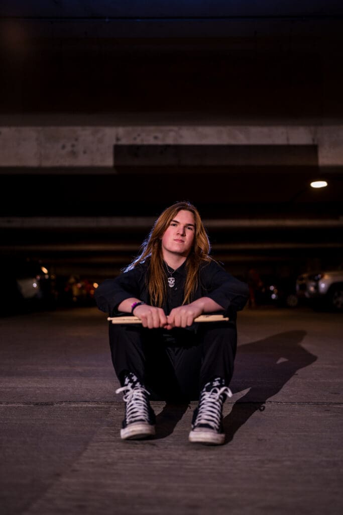 Senior with drum sticks in a parking garage in Columbus, Ohio.