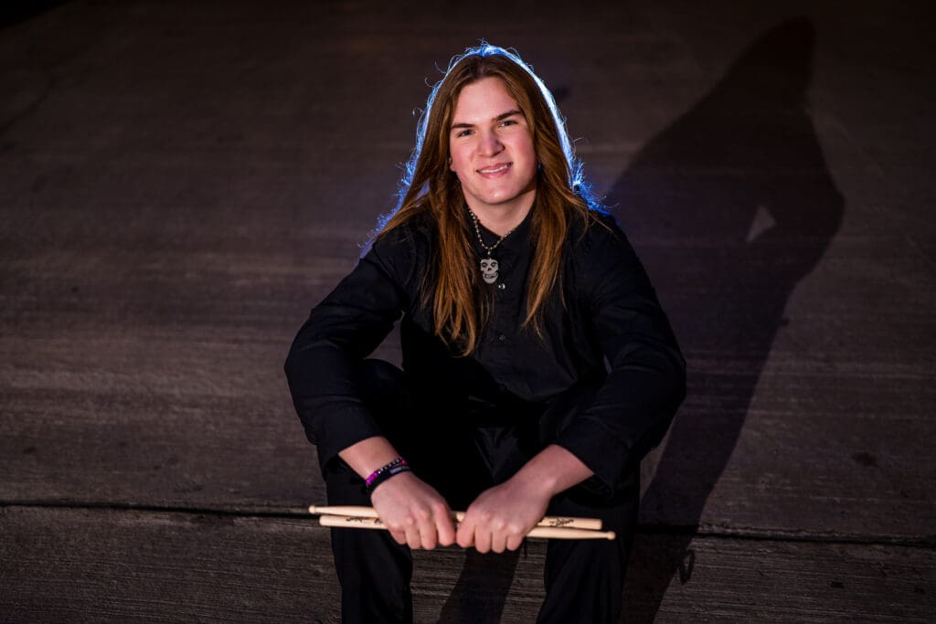Senior with drum sticks in a parking garage in Columbus, Ohio.