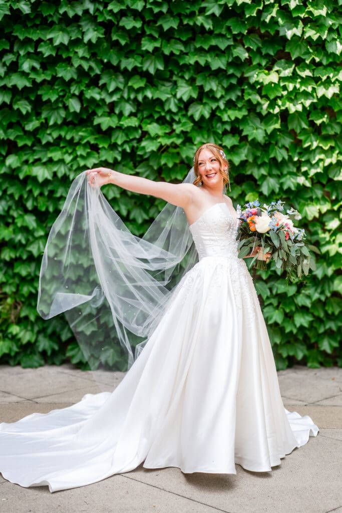 The bride playing with her veil in front of a vein wall at the Club at Corazon.