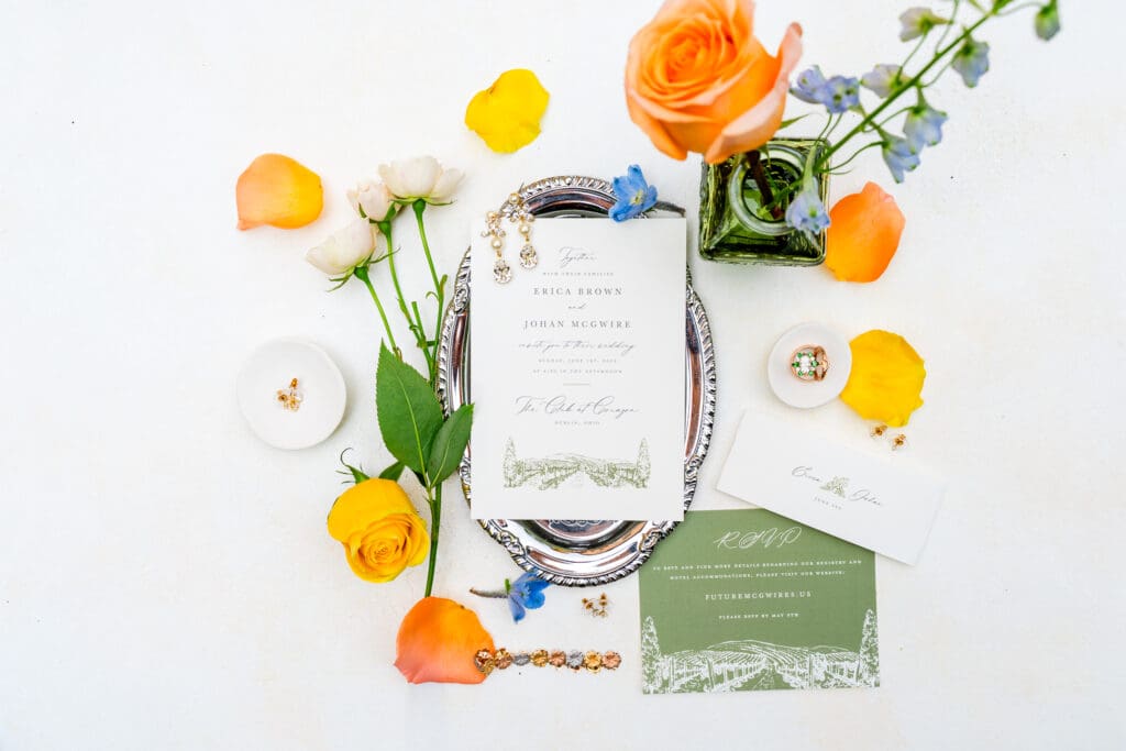 A colorful, summery flatlay with the wedding invitation, rings, and jewelry.
