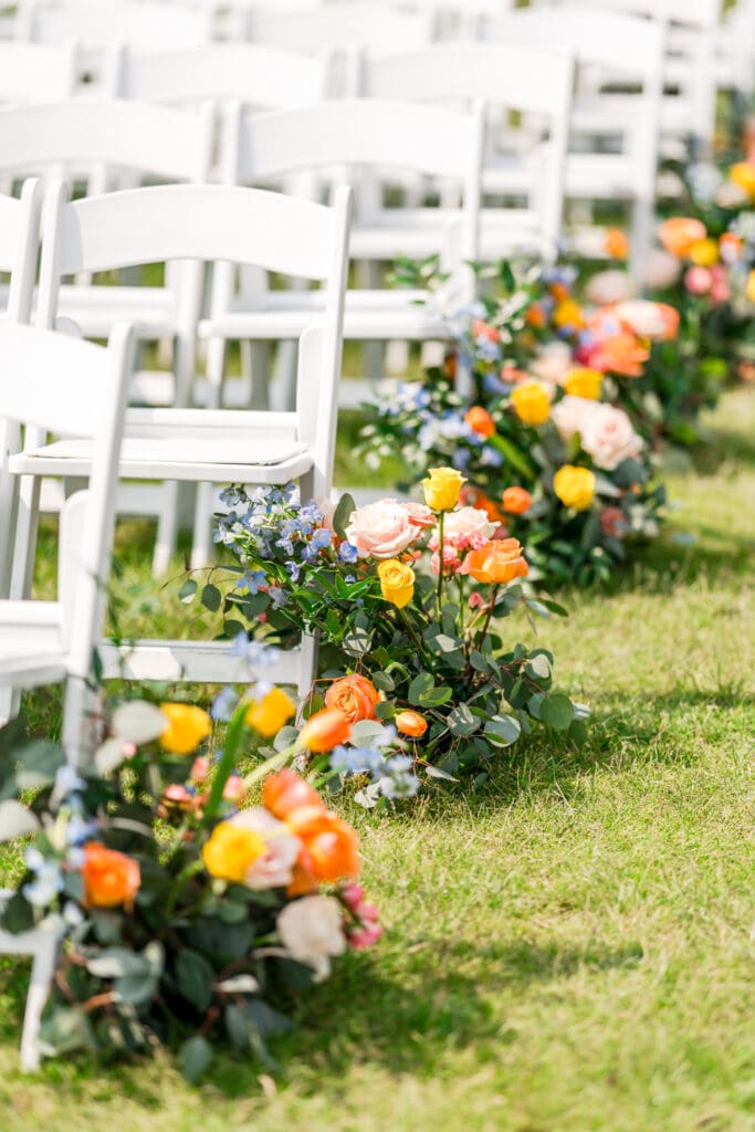 Colorful floral arrangements lining the ceremony aisle outside.