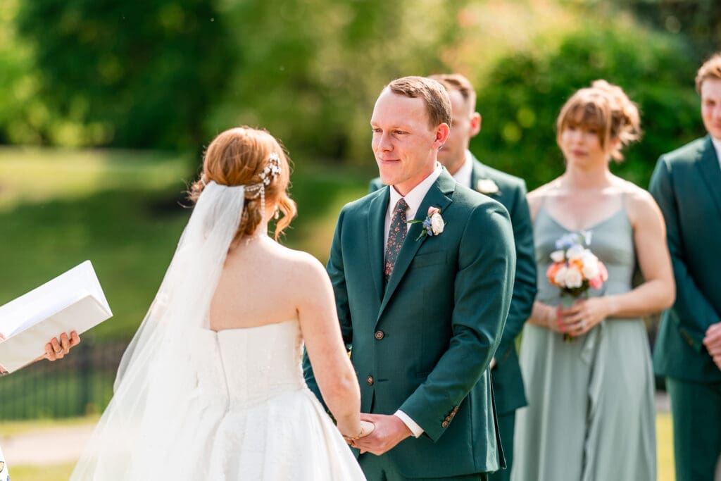 The groom looks lovingly at his bride during their outdoor ceremony.