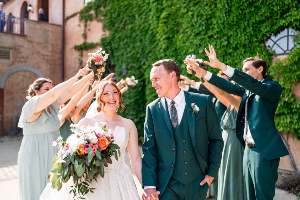 The wedding party creates a tunnel as the bride and group walk through.