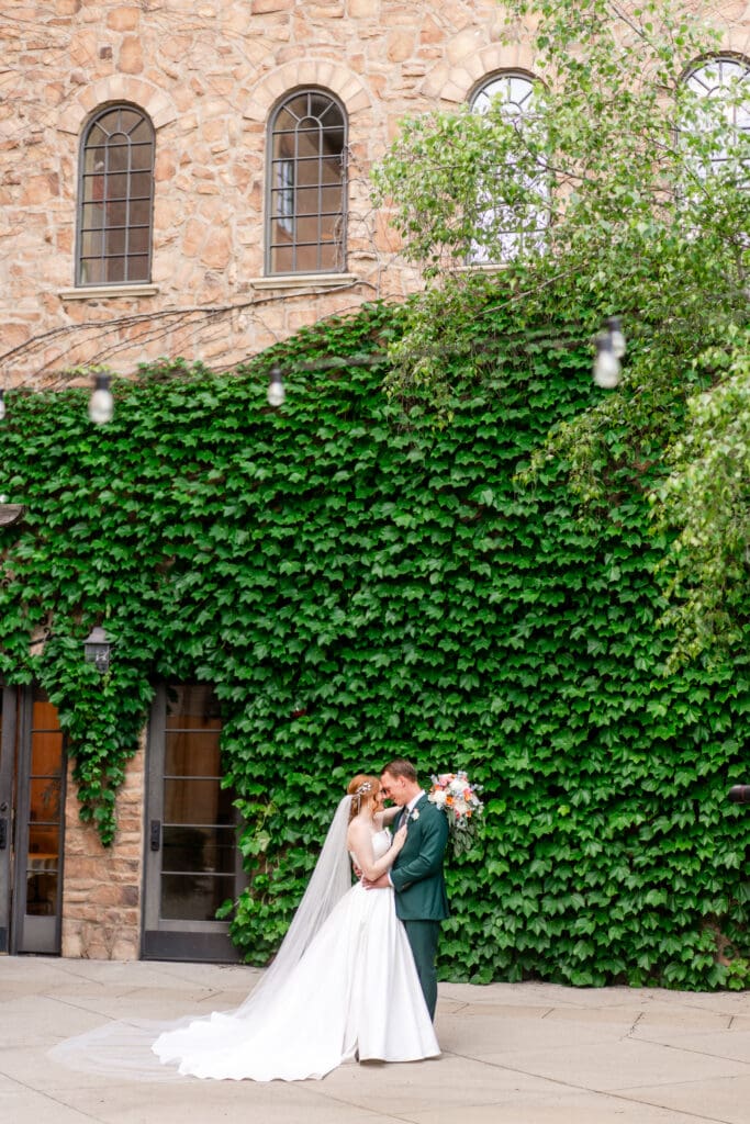 A wedding couple embraces in front of a stone wall covered in veins at the Club at Corazon in Columbus, Ohio.