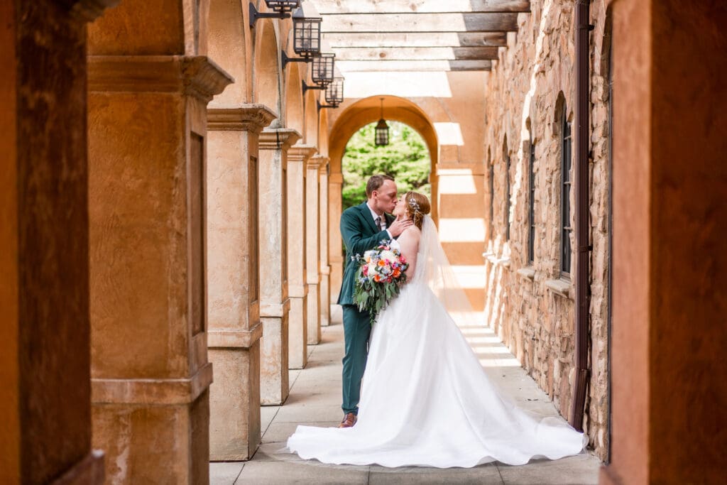 Bride and groom kiss under a pergola at the Club at Corazon.
