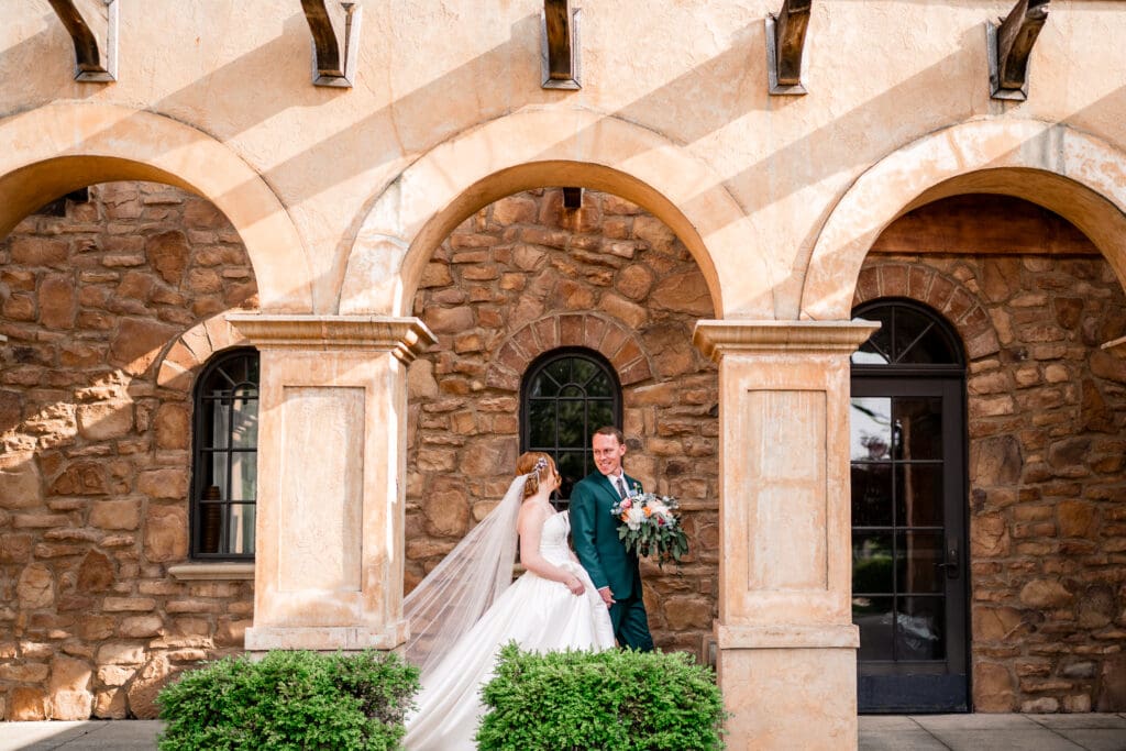 Bride and groom hold hands and walk through an archway at the Club at Corazon.