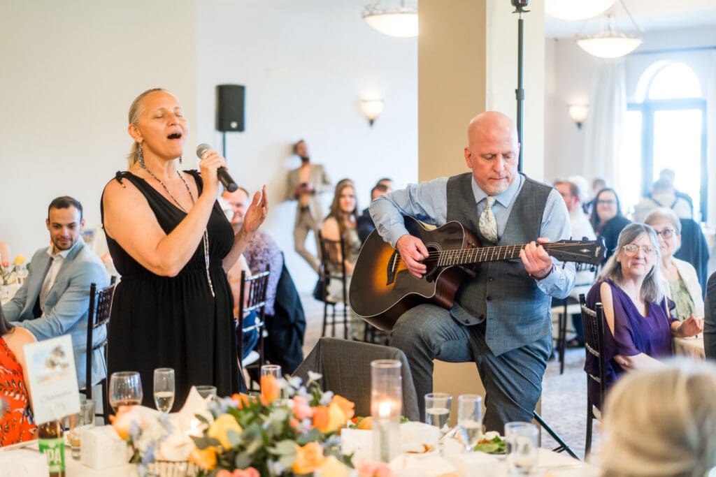 A man plays guitar while woman sings during the reception.