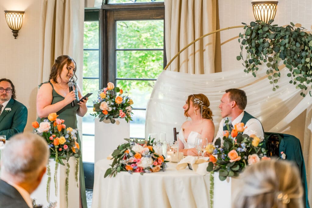 A bridesmaid and the wedding couple share a meaningful look during the bridesmaid's speech.