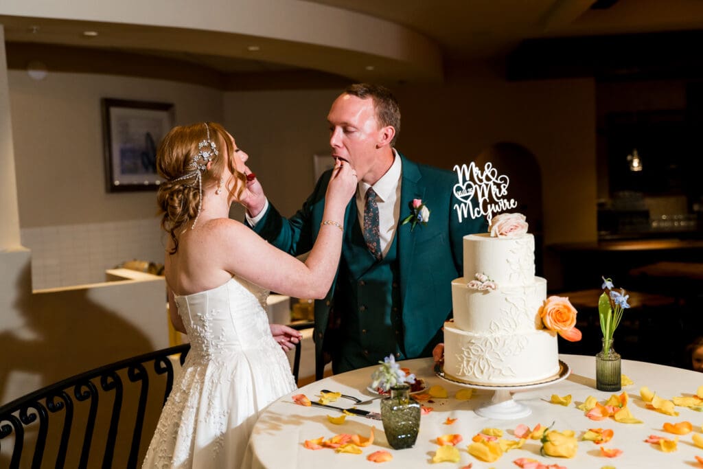 The bride and groom feed each other a piece of wedding cake.