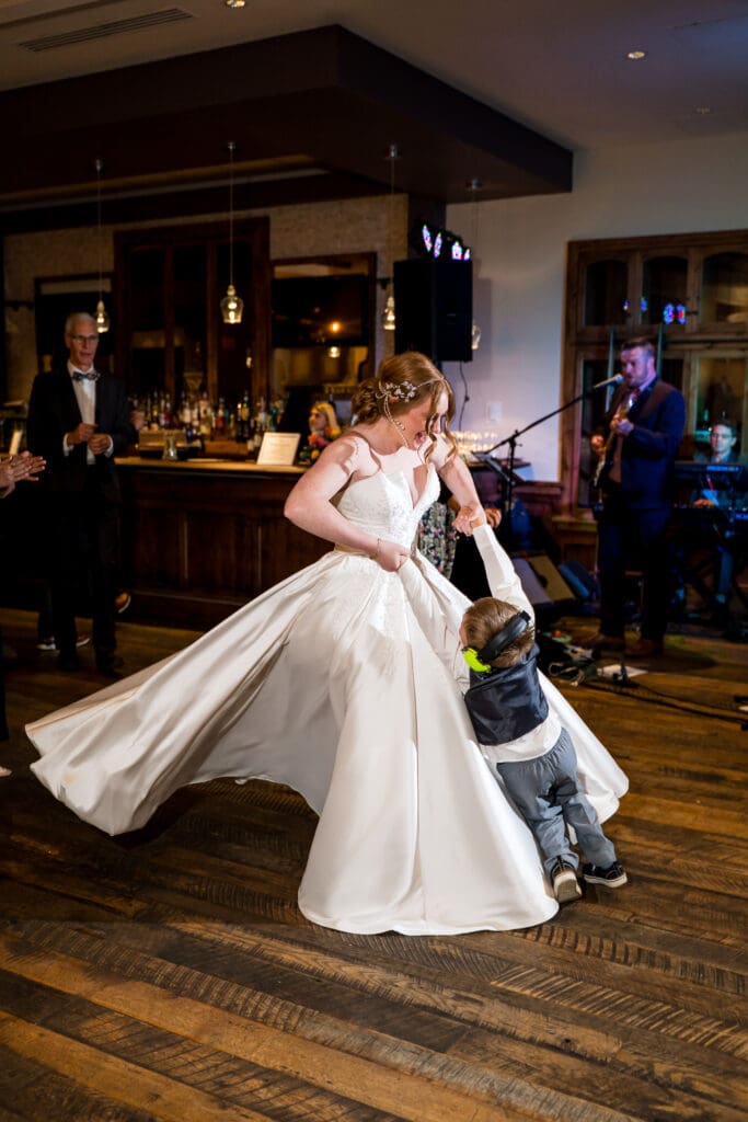 Bride spins and holds up her nephew as they dance on the dance floor.