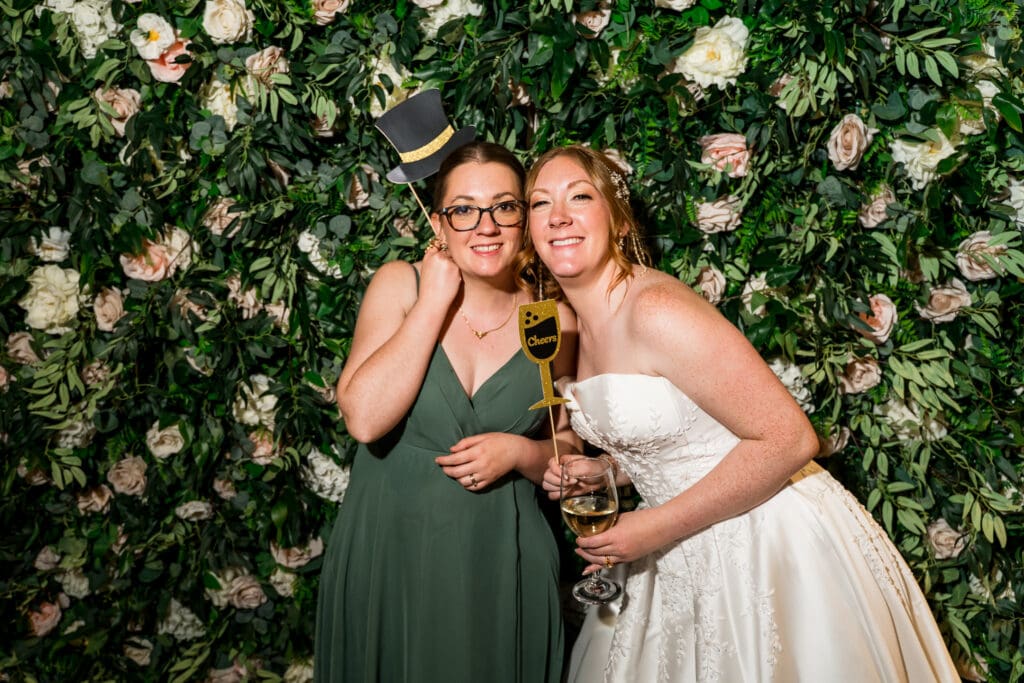 The bride and her sister hold props at their photobooth.