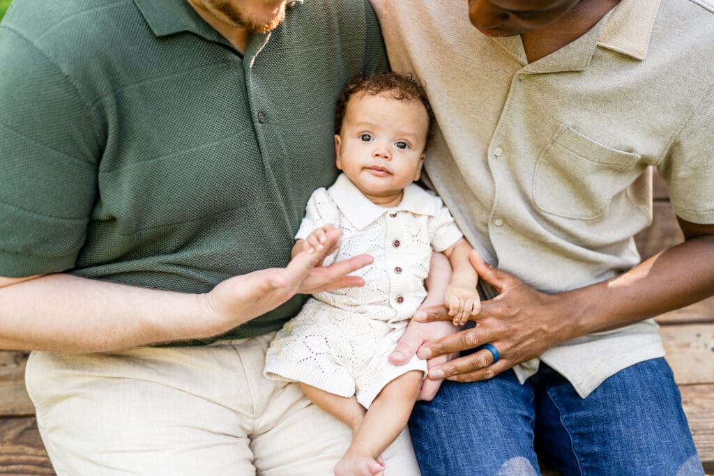 Two dads hold their baby boy.