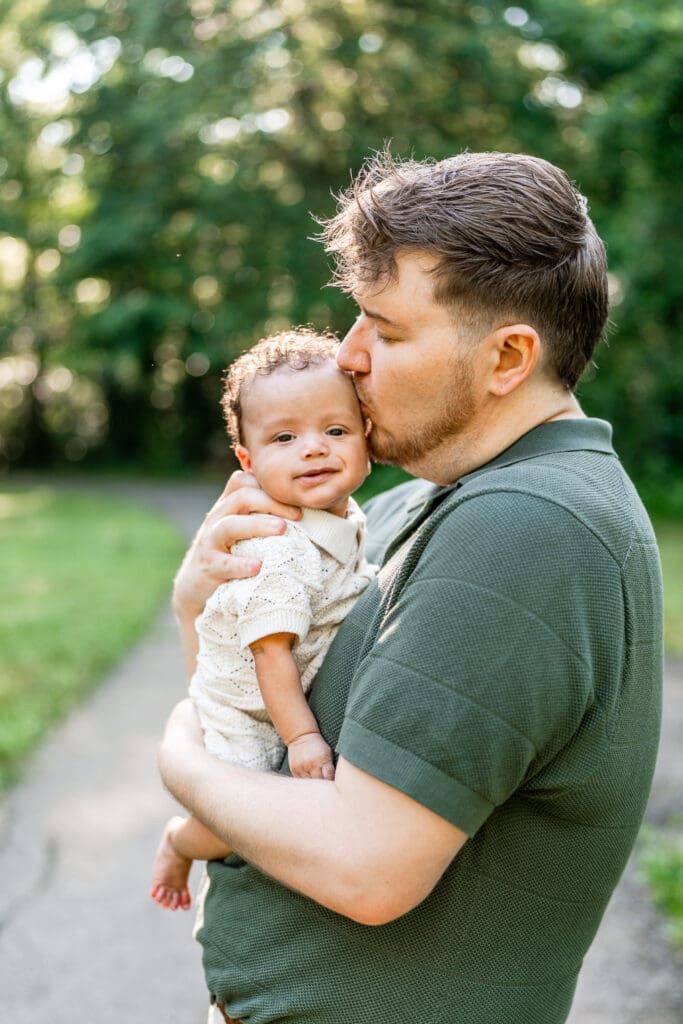 A dad holds his baby and kisses his head at Blacklick Metro Park.