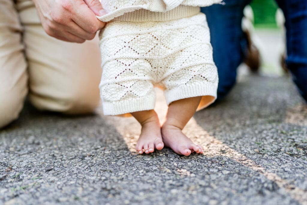 A baby boy's bare feet standing on an outdoor path.