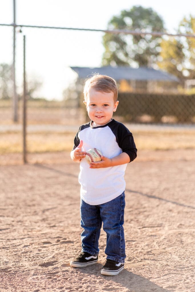 Little boy holding a baseball on a baseball field in Canal Winchester, Ohio.