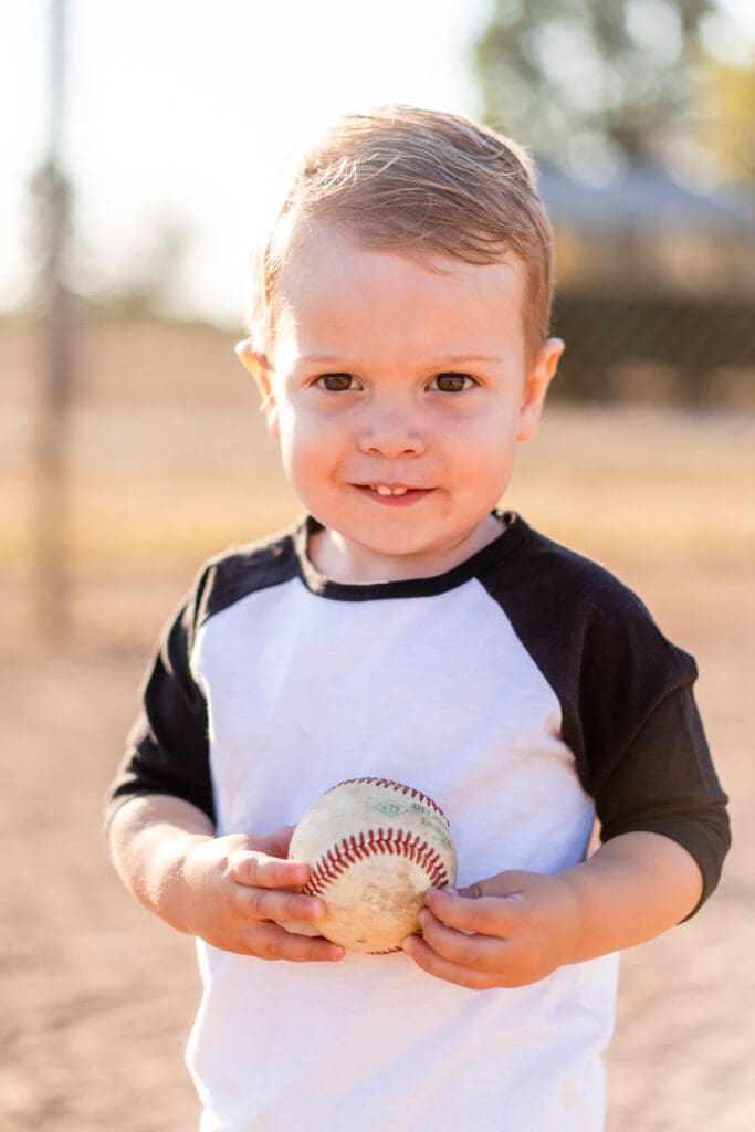 Little boy holding a baseball on a baseball field in Canal Winchester, Ohio.