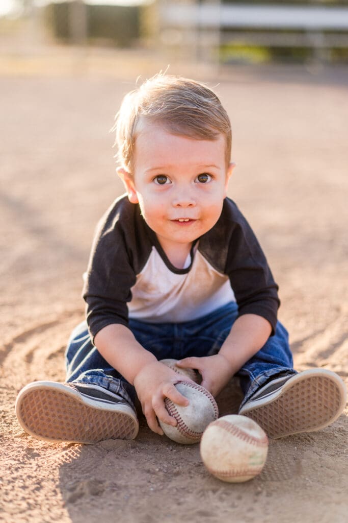 Little boy sits in the dirt on a baseball field in Canal Winchester, Ohio.