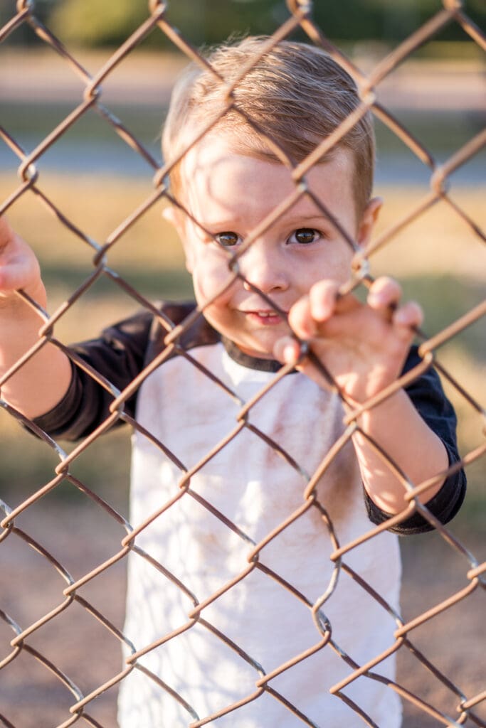 Little boy looks through the fence at a baseball field in Canal Winchester, Ohio.