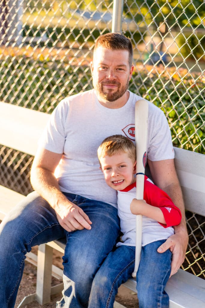 A boy and his father sit in the dugout at a baseball field in Canal Winchester, Ohio.
