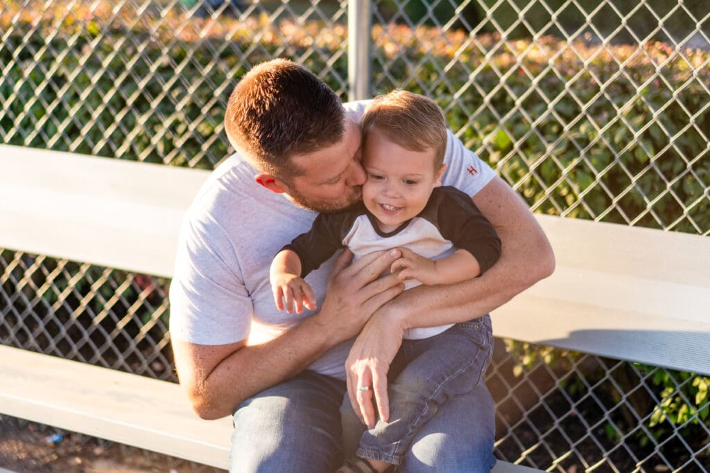 A boy and his father sit in the dugout at a baseball field in Canal Winchester, Ohio.