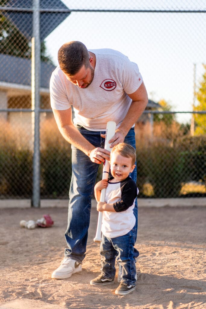 Little boy gets a lesson from his dad how to hold a bat.