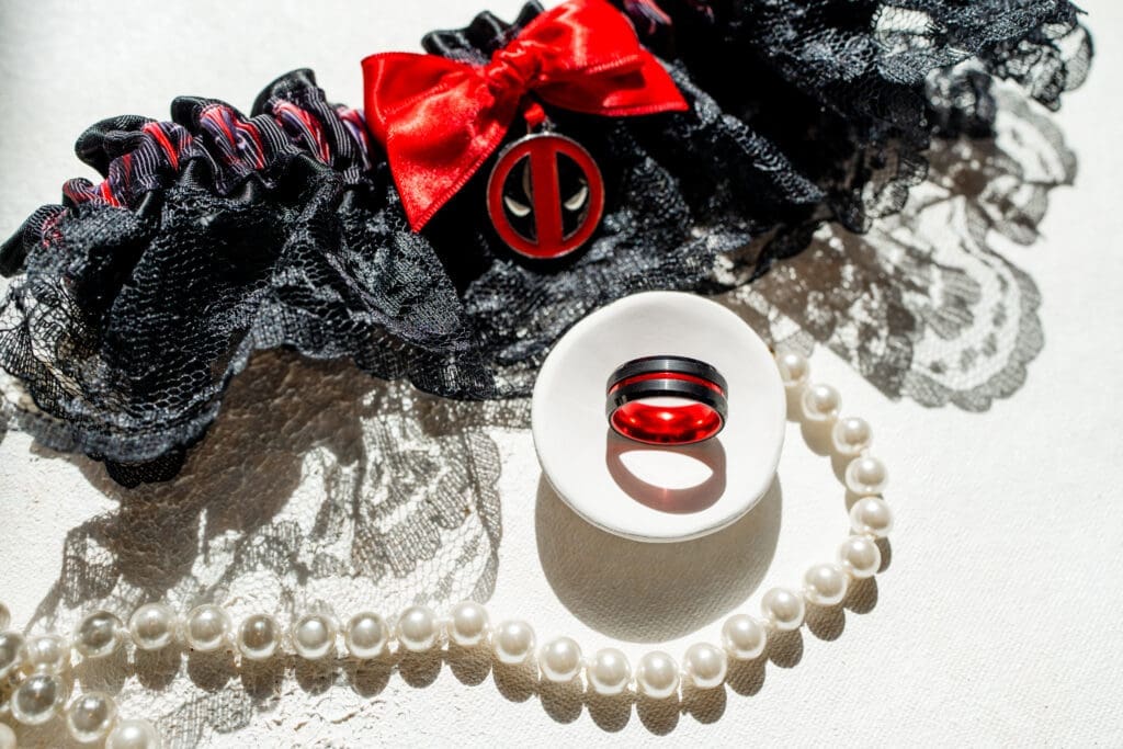 A direct sun flat lay of the garter, groom's ring, and the bride's necklace.