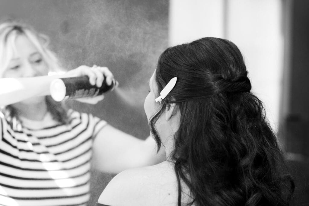 Bride getting setting spray onto her face as she gets ready.